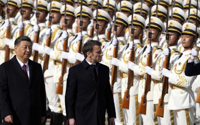 El presidente francés, Emmanuel Macron (d), inspecciona una guardia de honor con el presidente chino, Xi Jinping