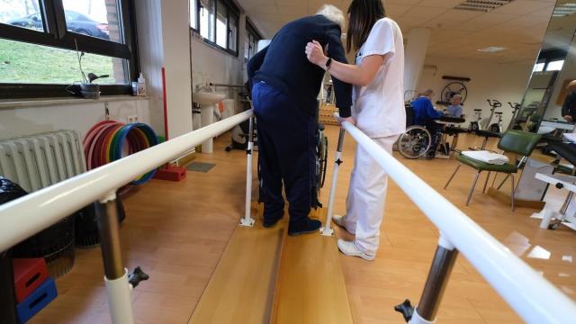 Una cuidadora ayuda a un anciano en una residencia para mayores.