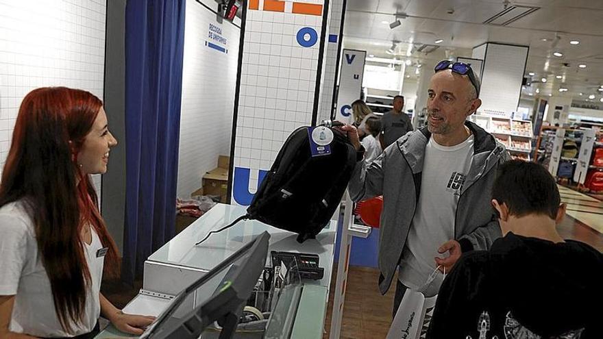 Un padre y su hijo, comprando una mochila para volver a las aulas con el material necesario.