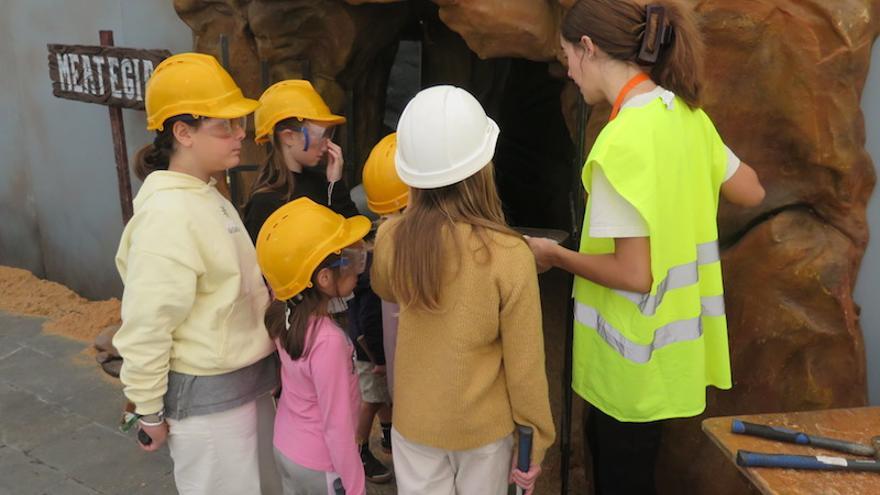 Una monitora imparte instrucciones a los niños que van a entrar en la mina del parque infantil.