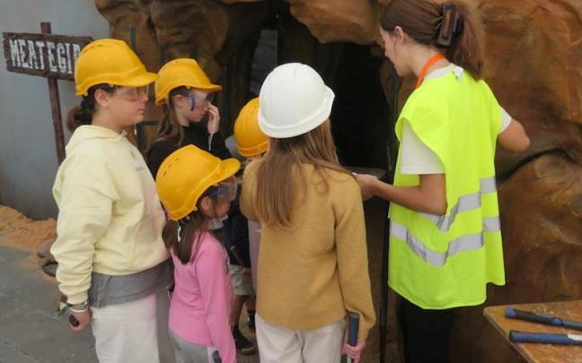Una monitora imparte instrucciones a los niños que van a entrar en la mina del parque infantil.