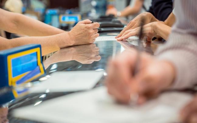 Varias personas rellenan documentos