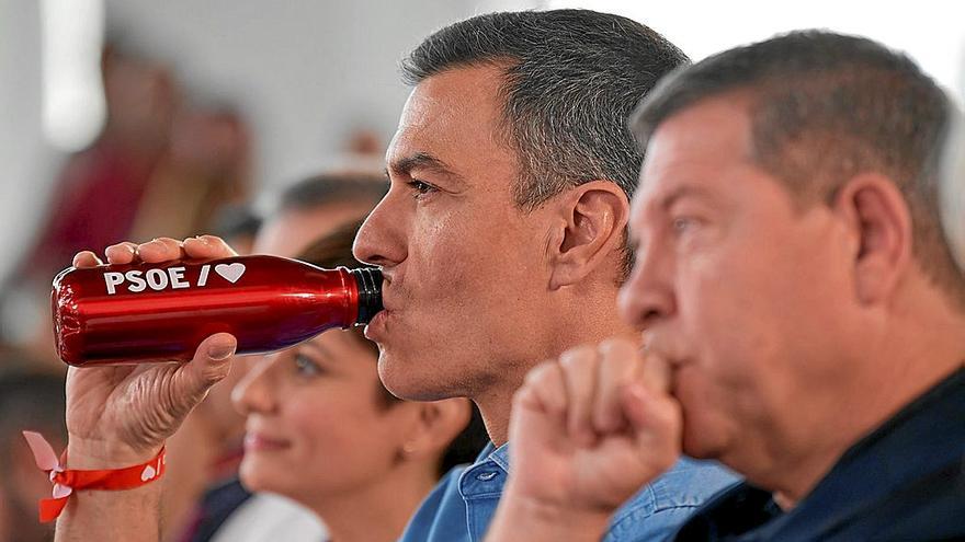 El presidente del Gobierno, Pedro Sánchez, bebe agua durante un acto de campaña en Castilla-La Mancha. En primer plano, García-Page.
