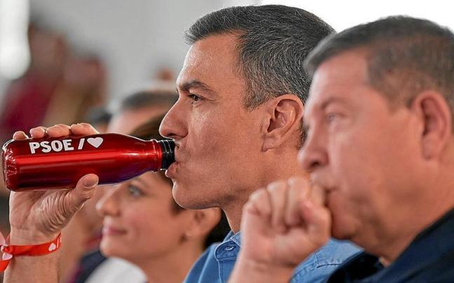 El presidente del Gobierno, Pedro Sánchez, bebe agua durante un acto de campaña en Castilla-La Mancha. En primer plano, García-Page.