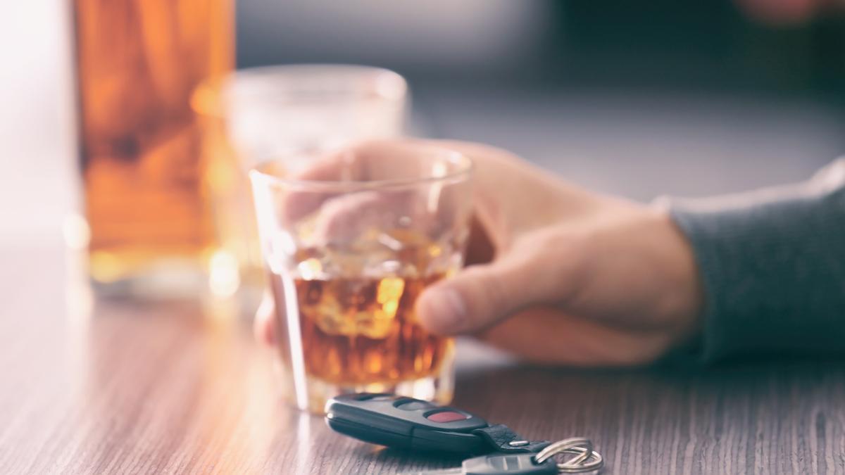 Una persona, bebiendo alcohol con las llaves del coche sobre la mesa.