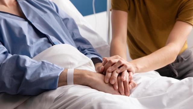 Una persona entrelaza sus manos con las de un familiar hospitalizado. Una persona entrelaza sus manos con las de un familiar hospitalizado.