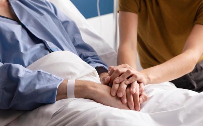Una persona entrelaza sus manos con las de un familiar hospitalizado. Una persona entrelaza sus manos con las de un familiar hospitalizado.