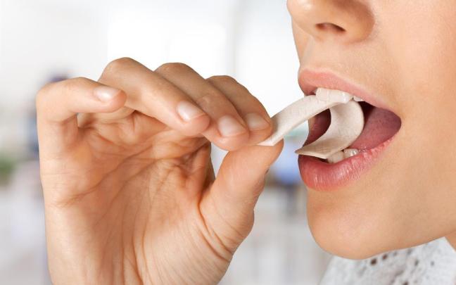 Una mujer se mete un chicle a la boca.