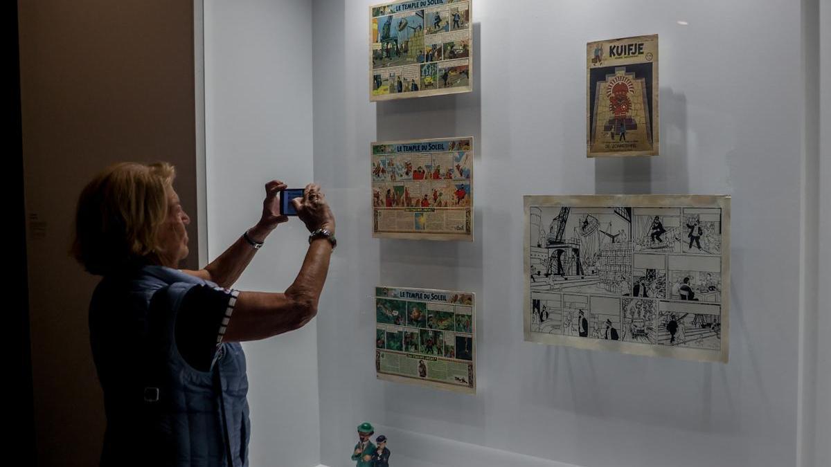 Una mujer fotografía algunas de las primeras viñetas de Tintín en una exposición.