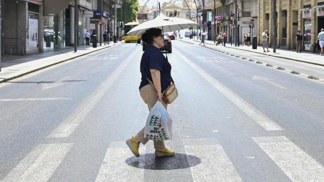 Una mujer se protege del sol con un paraguas.
