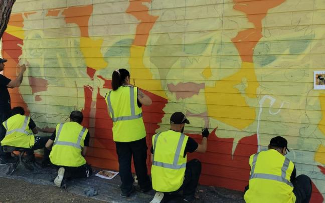El equipo del taller de empleo sobre murales de Amurrio trabajando en el txoko laranja del parque Juan Urrutia