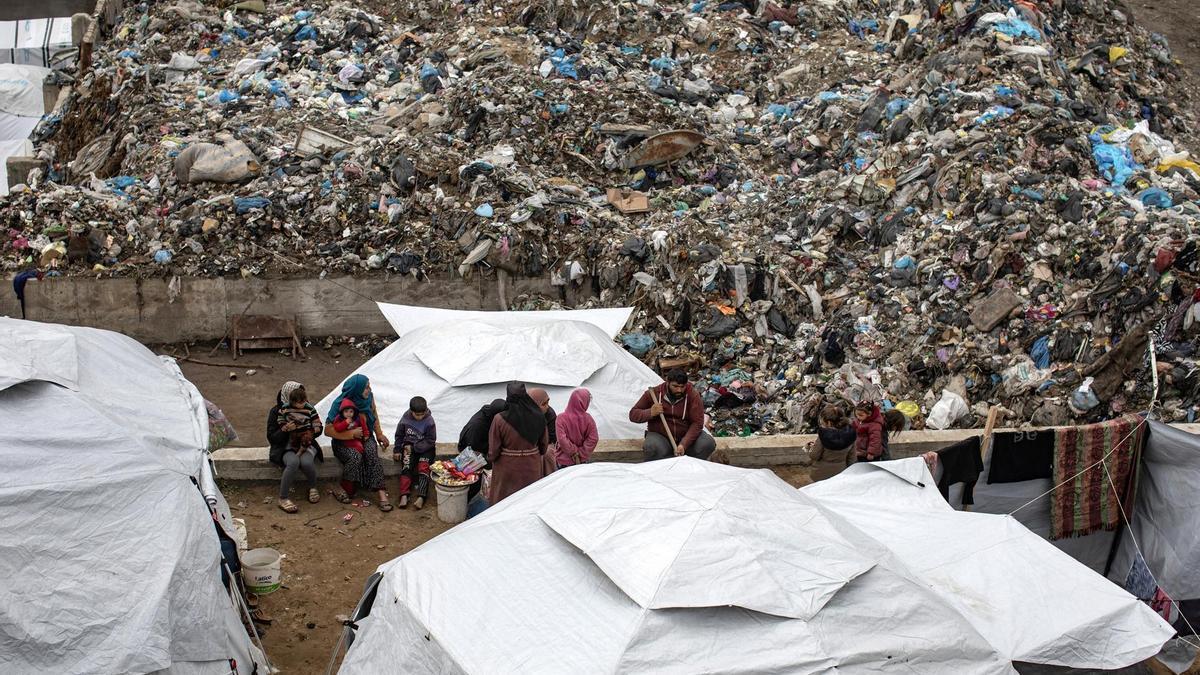 Palestinos desplazados se sientan junto a tiendas de campaña en un campamento instalado en un vertedero de basura en la zona de Yarmuk, en la ciudad de Gaza