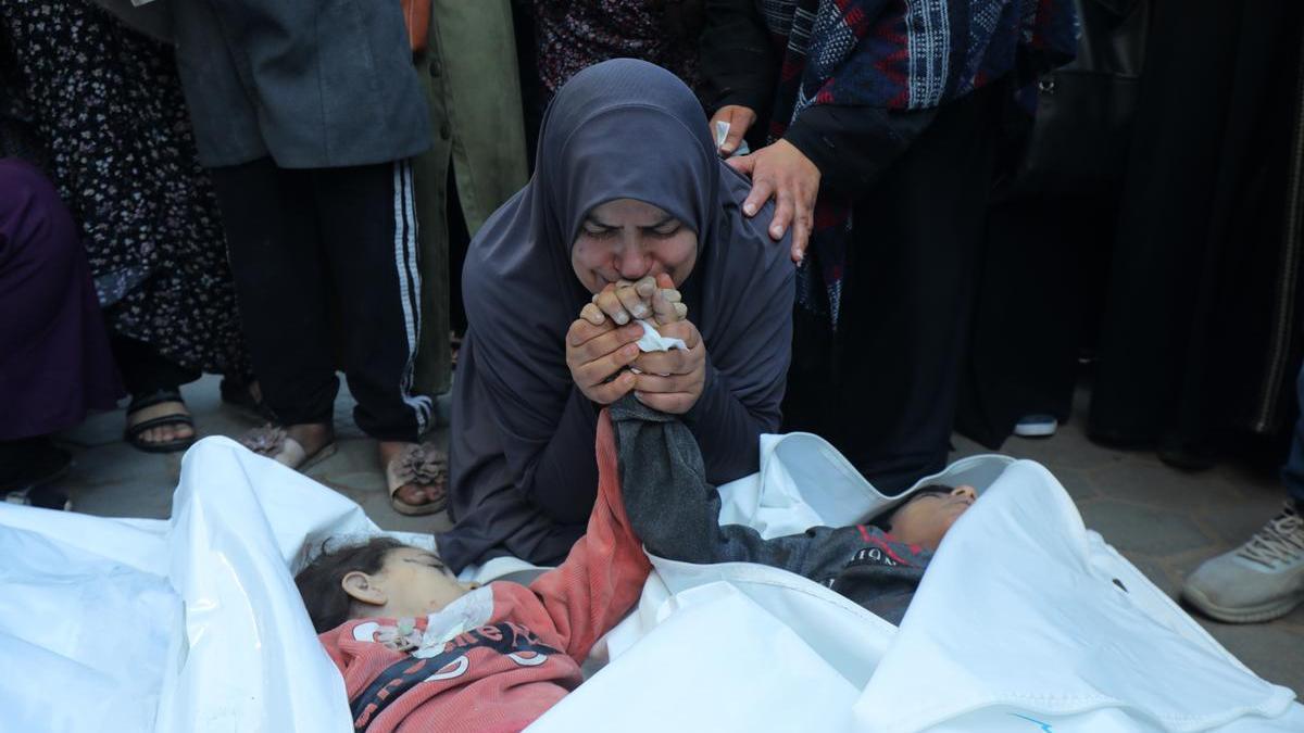 Una mujer se despide de sus hijos, que murieron en un ataque israelí a un campo de refugiados en el centro de Gaza.