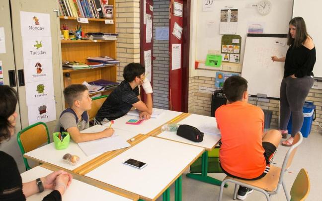 Un grupo de alumnos atiende las explicaciones de una profesora en clase de matemáticas.