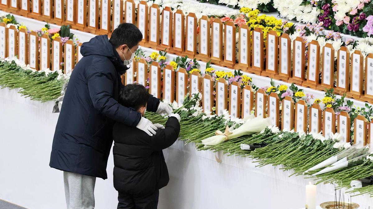 Un niño y su padre depositan flores en un altar en recuerdo a las víctimas del accidente aéreo en Seúl.