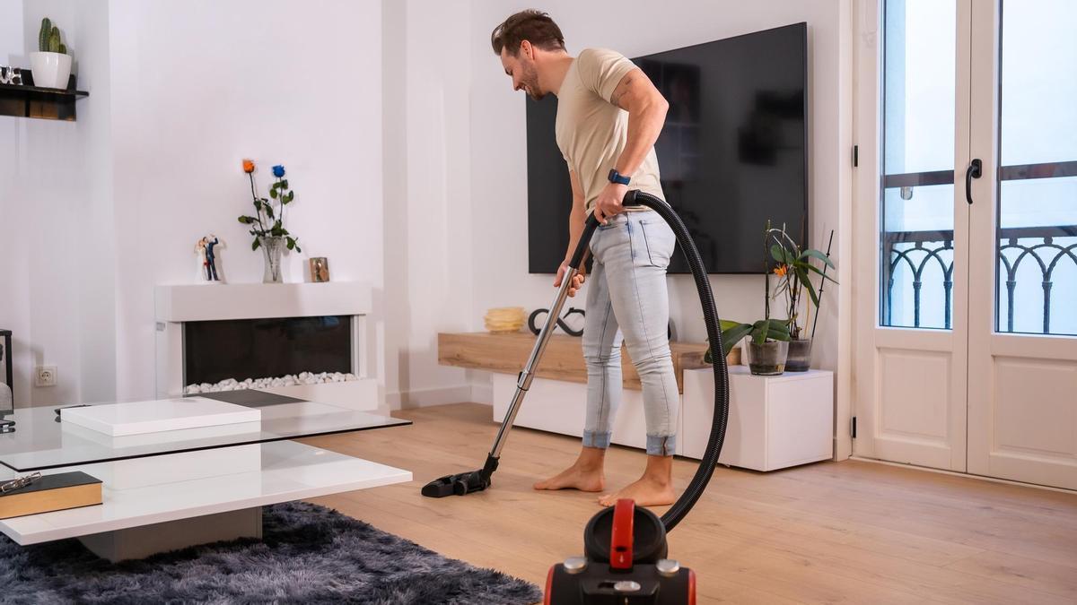 Un hombre pasa el aspirador por el salón.