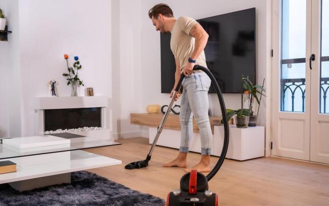 Un hombre pasa el aspirador por el salón.