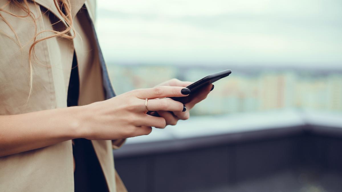 Una mujer revisa los SMS en su teléfono móvil.