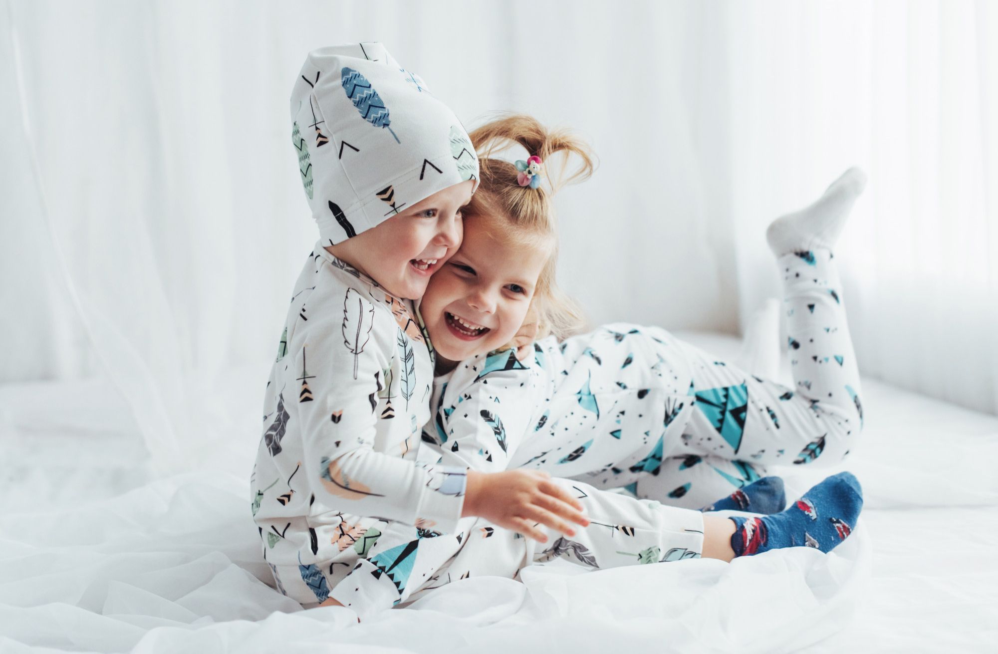 Simpática pose de dos pequeños en pijama sobre la cama.