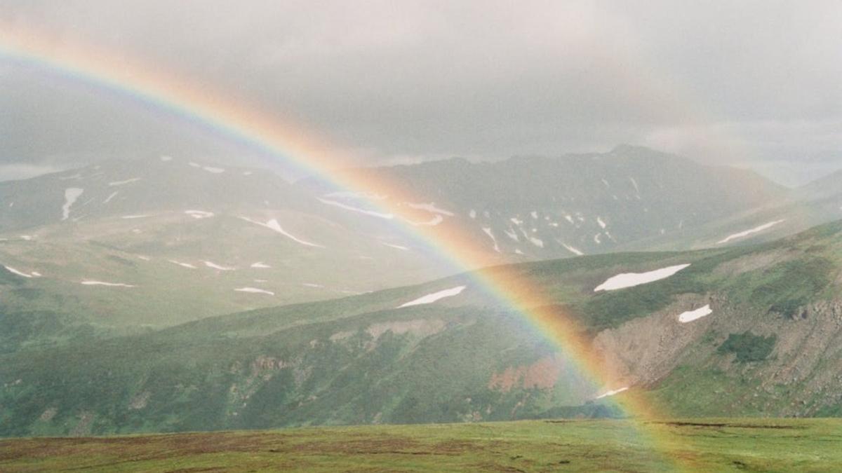 Imagen de un arco iris en un valle montañoso