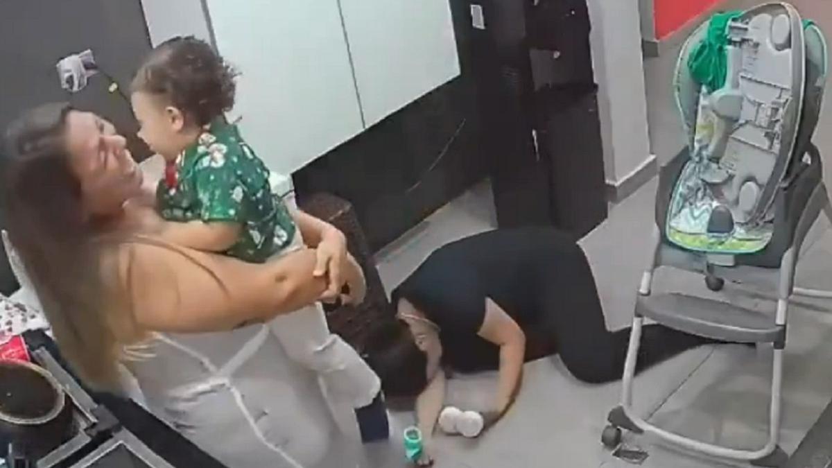 La madre muerta de risa en el suelo y su amiga con el bebé.