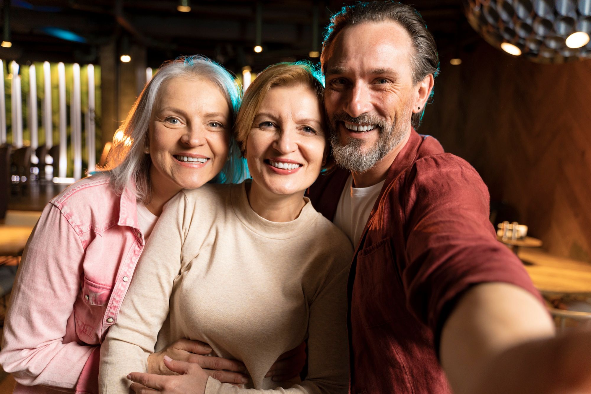 Tres adultos mayores se hacen un selfie en un restaurante.