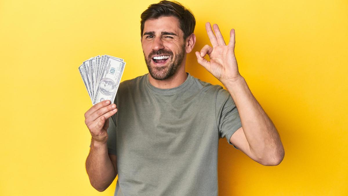 Un hombre, feliz con un fajo de billetes.