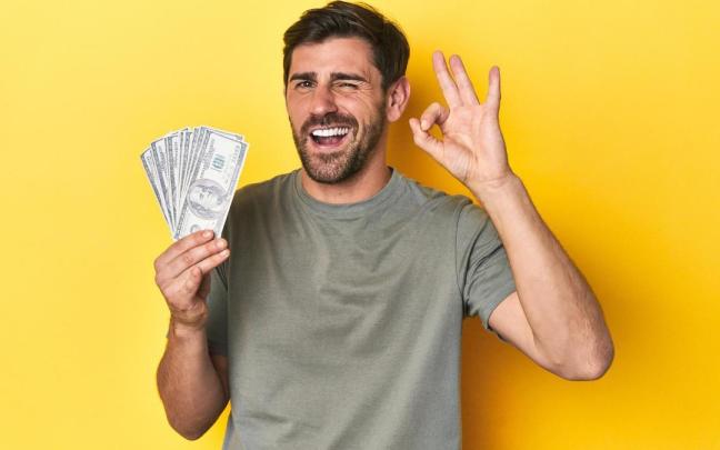 Un hombre, feliz con un fajo de billetes.