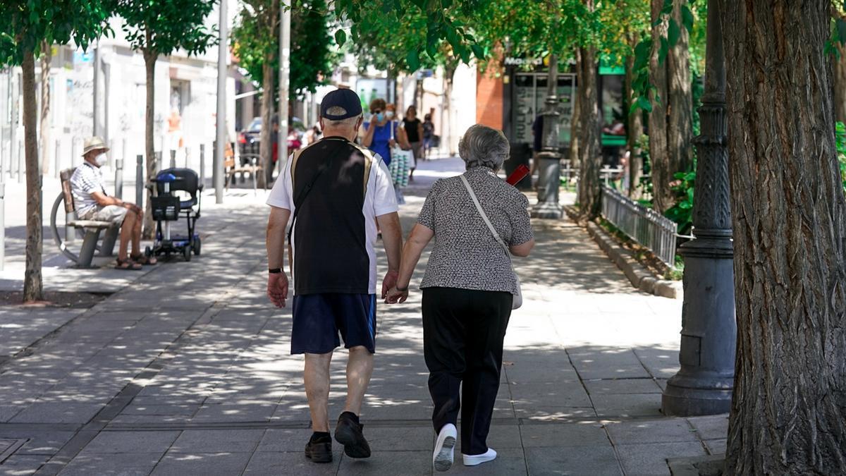 Una pareja de jubilados pasea por la calle.