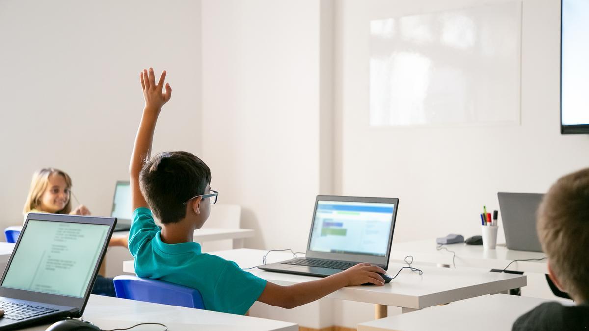 Un niño levanta la mano en clase para contestar una pregunta del docente.