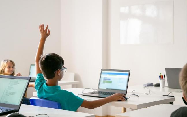 Un niño levanta la mano en clase para contestar una pregunta del docente.