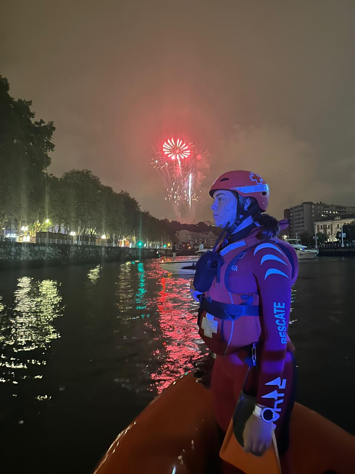 Una integrante de la Cruz Roja posa con fuegos artificiales a sus espaldas.