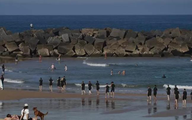 Bañistas y paseantes disfrutan este miércoles de un día soleado en la playa de la Zurriola de San Sebastián.
