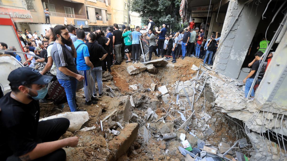 Un grupo de personas junto a un edificio bombardeado en Beirut.