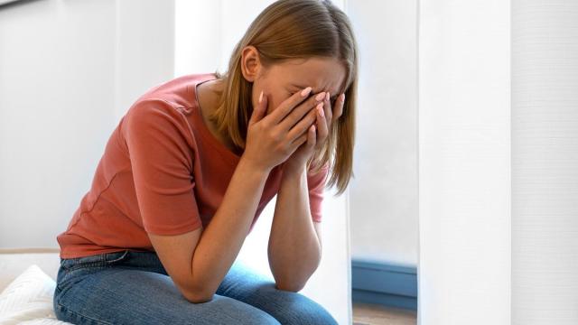 Una mujer triste y apática sentada en la cama.