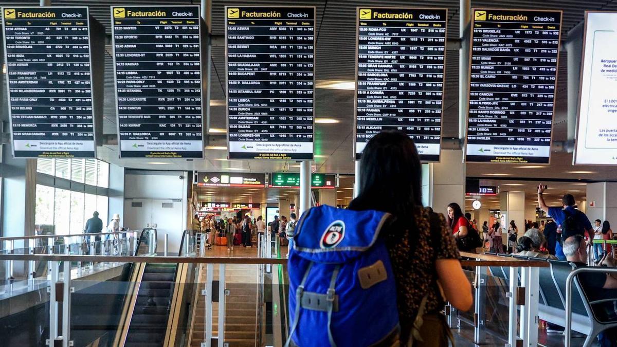 Imagen de una pasajera frente a las pantallas de información en un aeropuerto