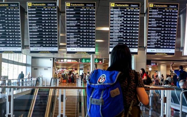Imagen de una pasajera frente a las pantallas de información en un aeropuerto