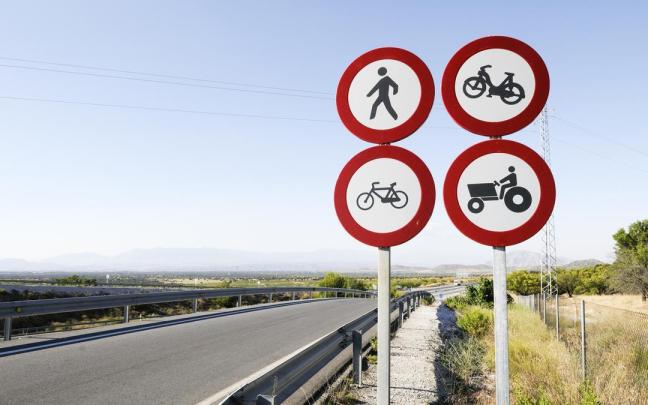 Cuatro señales de tráfico en la carretera.