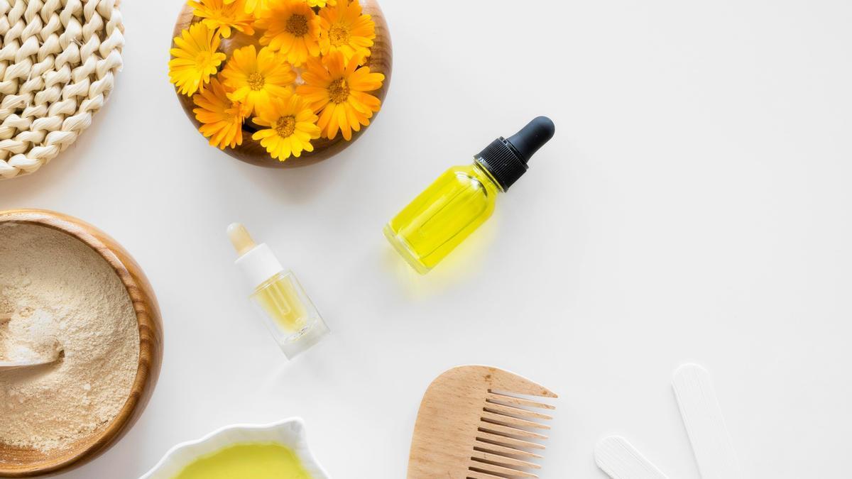 Flores de árnica junto a varios cosméticos naturales.