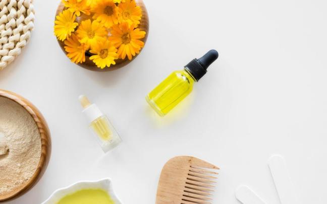 Flores de árnica junto a varios cosméticos naturales.