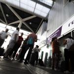 Varias personas hacen cola ante una oficina de Renfe en una estación.