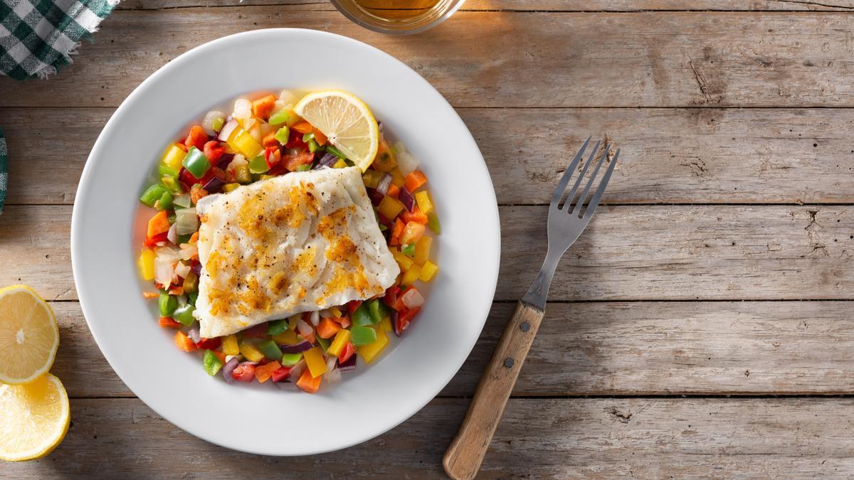 Un plato de pescado con guarnición de verduras.