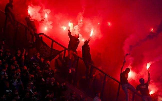Un grupo de aficionados enciende bengalas en un partido de fútbol.
