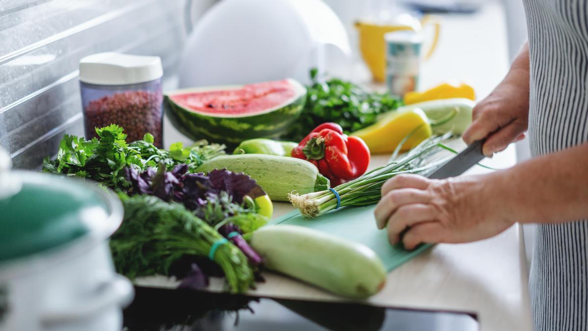 Una mujer cortando verduras.