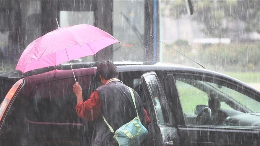 Una persona se mete en el interior de su vehículo en plena tormenta de verano.