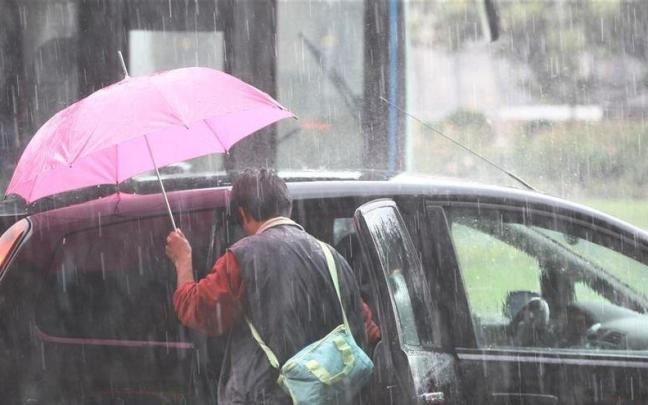 Una persona se mete en el interior de su vehículo en plena tormenta de verano. Una persona se mete en el interior de su vehículo en plena tormenta de verano.
