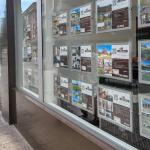 Una mujer pasea frente a una inmobiliaria