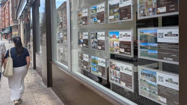 Una mujer pasea frente a una inmobiliaria