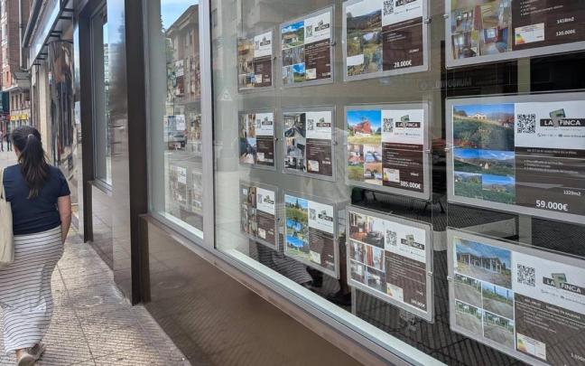 Una mujer pasea frente a una inmobiliaria