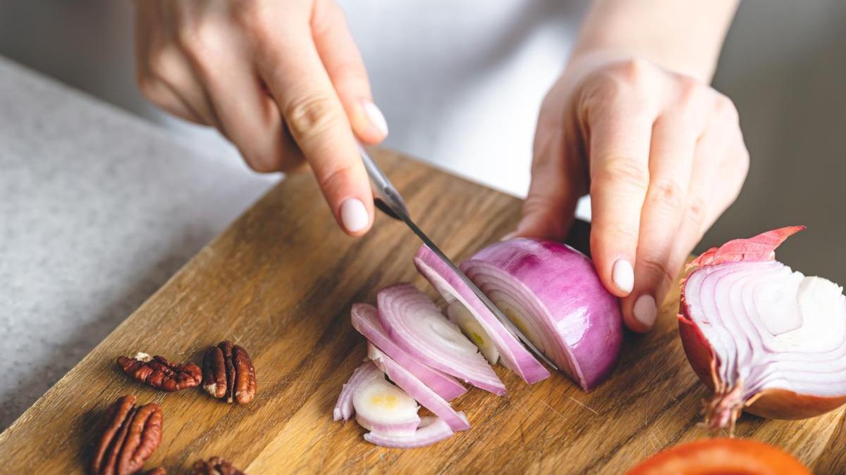 Manos de una chica cortando cebolla morada